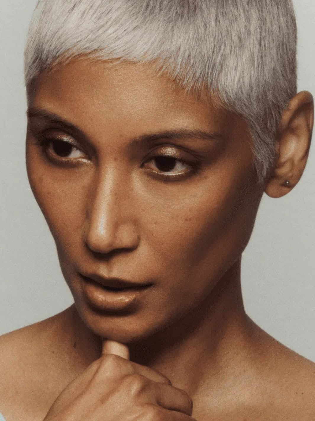 Person with short, styled hair using 19/99 Beauty Cream Contour Stick in 'Kave' against a neutral background | Twentyseven Toronto