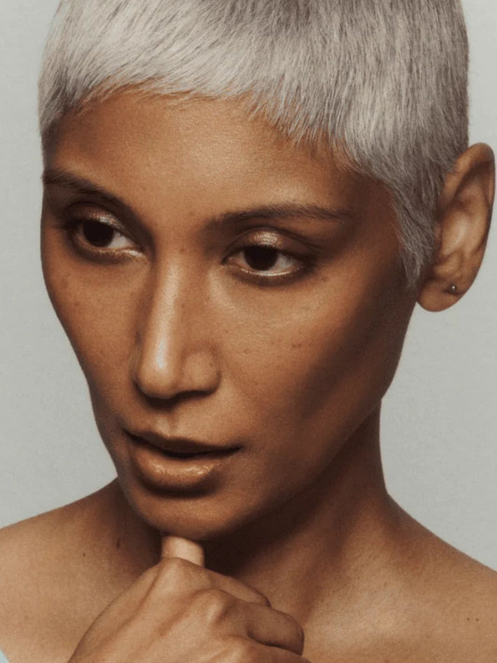 Person with short, styled hair using 19/99 Beauty Cream Contour Stick in 'Kave' against a neutral background | Twentyseven Toronto