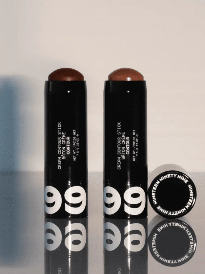 Two cream contour sticks in shades 'Tea' and 'Kave' with 19/99 Beauty branding and black packaging on a reflective surface | Twentyseven Toronto