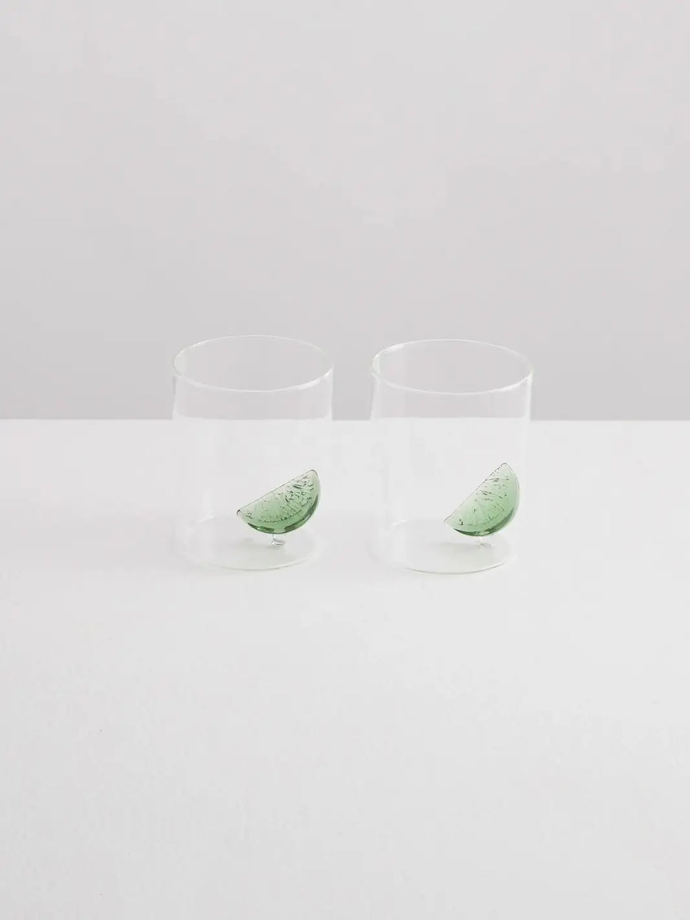 Two clear gin and tonic gobelets with glass lime wedges from Maison Balzac on a white background | Twentyseven Toronto