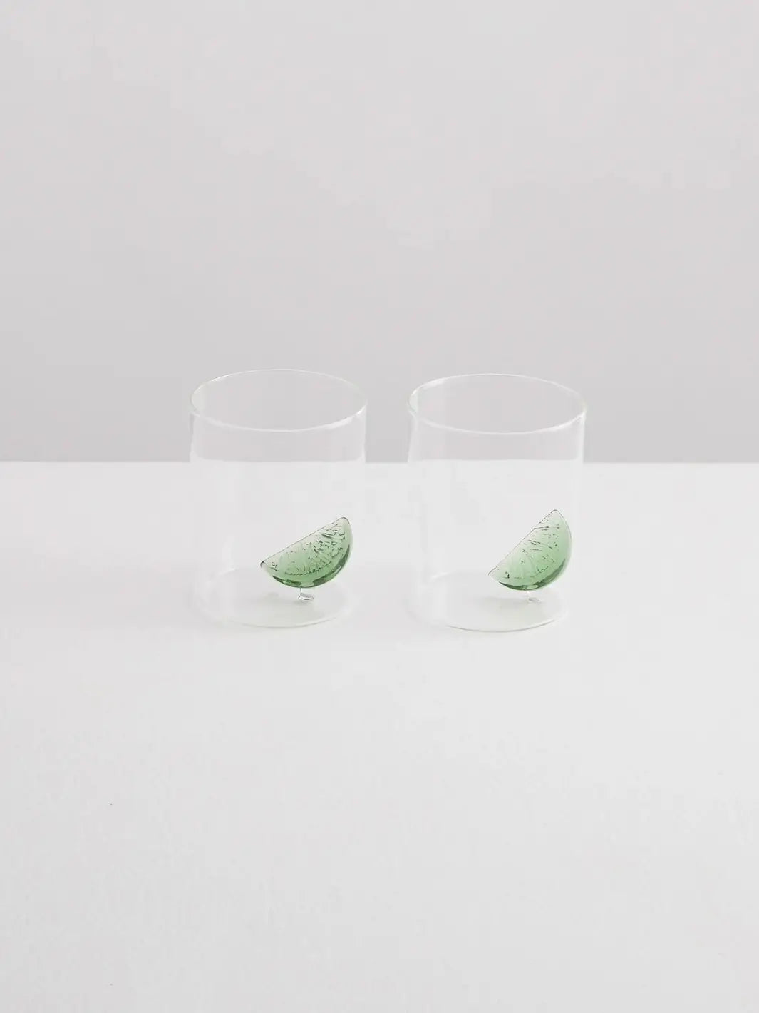 Two clear gin and tonic gobelets with glass lime wedges from Maison Balzac on a white background | Twentyseven Toronto