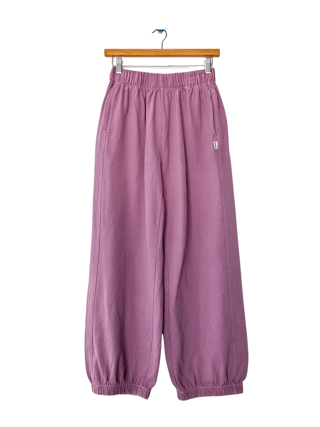 A studio product shot of the Le Bon Shoppe Balloon Pants in Dusty Lilac hanging on a wooden clip hanger | Twentyseven