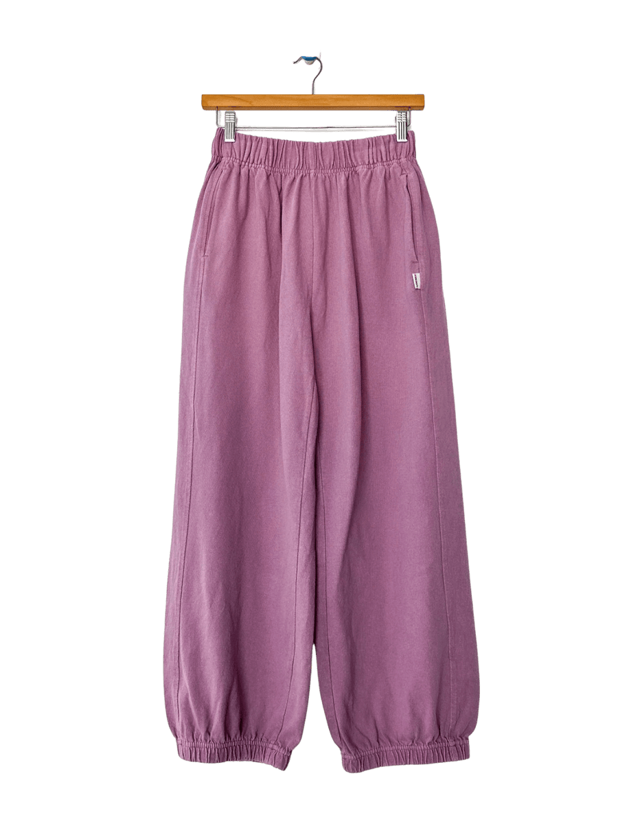 A studio product shot of the Le Bon Shoppe Balloon Pants in Dusty Lilac hanging on a wooden clip hanger | Twentyseven