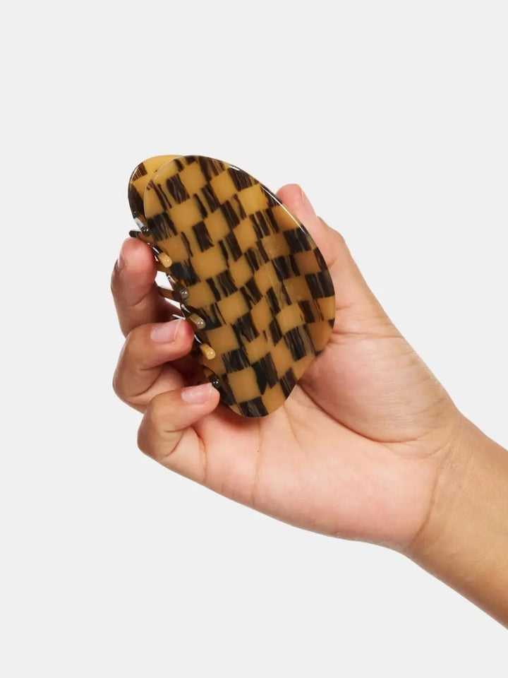 A hand holding the closed Chunks Checker Claw in Mocha to display its brown and tan checkered pattern | Twentyseven