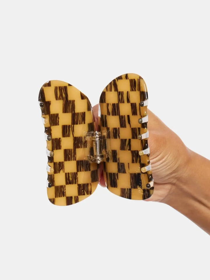 A hand holding open the Chunks Checker Claw in Mocha showing the inner spring and teeth mechanism | Twentyseven