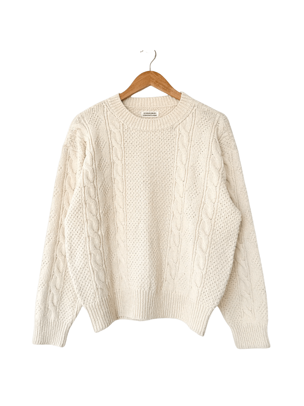 A flat lay product shot of the Le Bon Shoppe Cotton Fisherman Sweater in Naturel displayed on a wooden hanger | Twentyseven