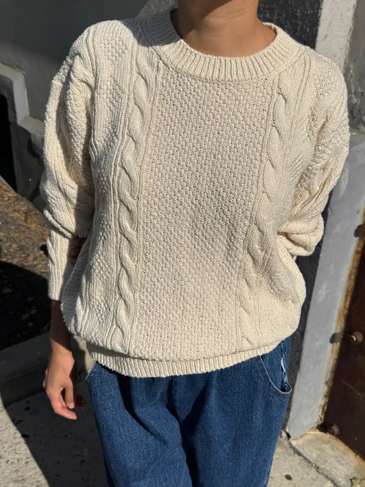 A close-up front view of a model wearing the cream-colored Le Bon Shoppe Cotton Fisherman Sweater in Naturel paired with blue jeans | Twentyseven
