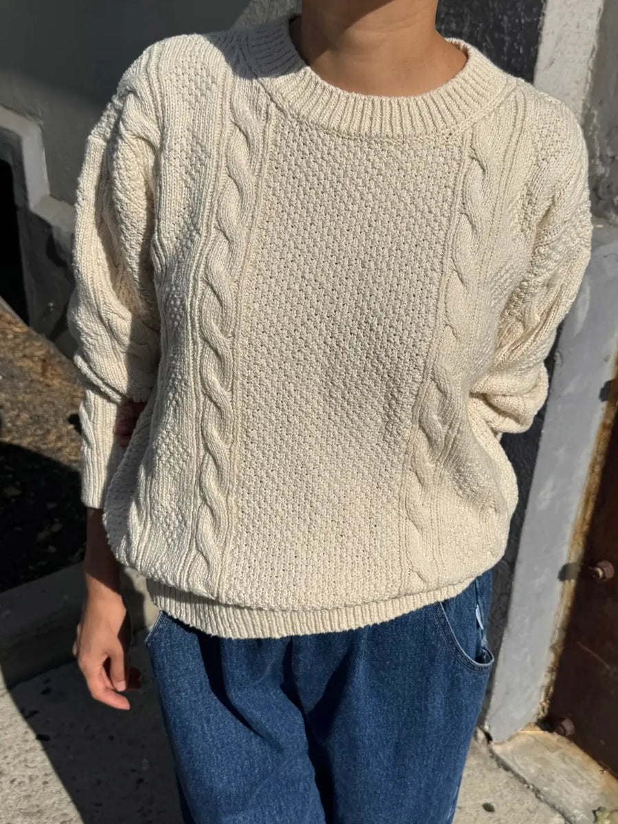 A close-up front view of a model wearing the cream-colored Le Bon Shoppe Cotton Fisherman Sweater in Naturel paired with blue jeans | Twentyseven