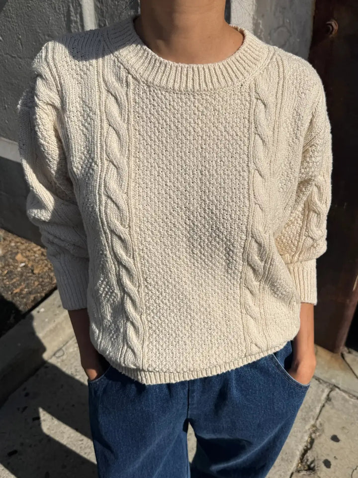 A front view shot of a model standing outdoors with hands in pockets wearing the Le Bon Shoppe Cotton Fisherman Sweater in Naturel | Twentyseven