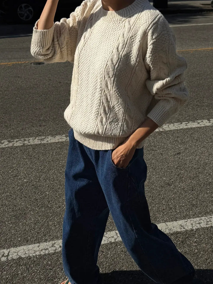 A full-length outdoor shot of a model crossing the street wearing the Le Bon Shoppe Cotton Fisherman Sweater in Naturel with wide-leg jeans | Twentyseven