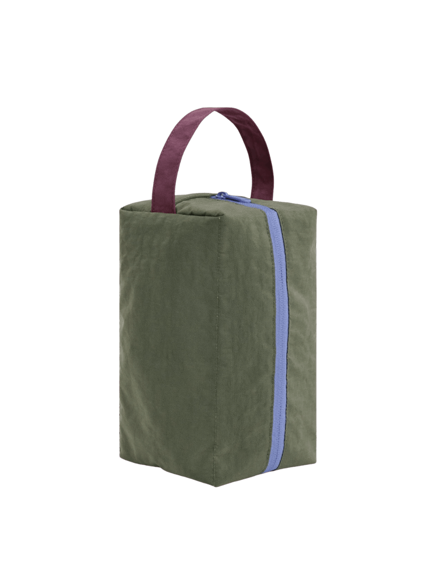 A studio product shot of the fully zipped dark green BAGGU Dopp Kit in Caper Mix with a dark red handle standing upright | Twentyseven