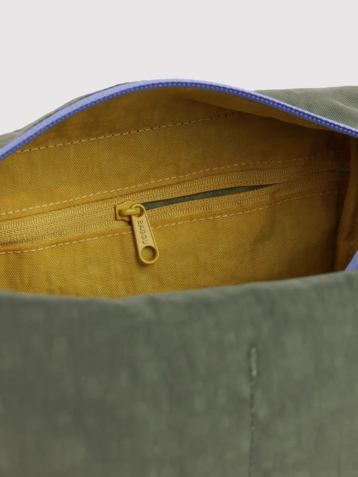 A close-up shot highlighting the mustard yellow interior lining and internal zippered pocket of the dark green BAGGU Dopp Kit in Caper Mix | Twentyseven