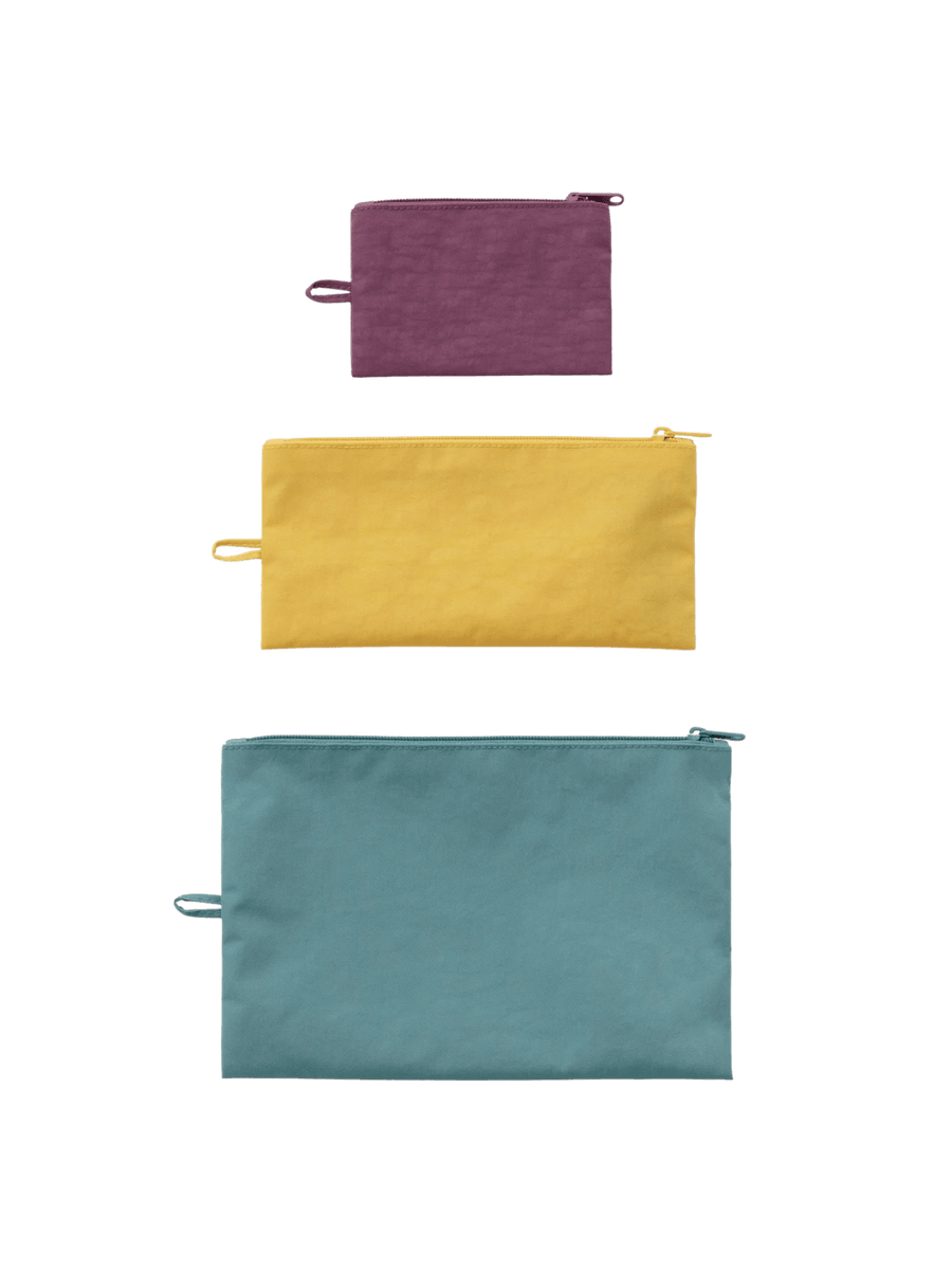 A top-down product shot of the BAGGU Flat Pouch Set in Jewel Mix featuring small purple, medium yellow, and large teal zippered pouches lined up vertically | Twentyseven