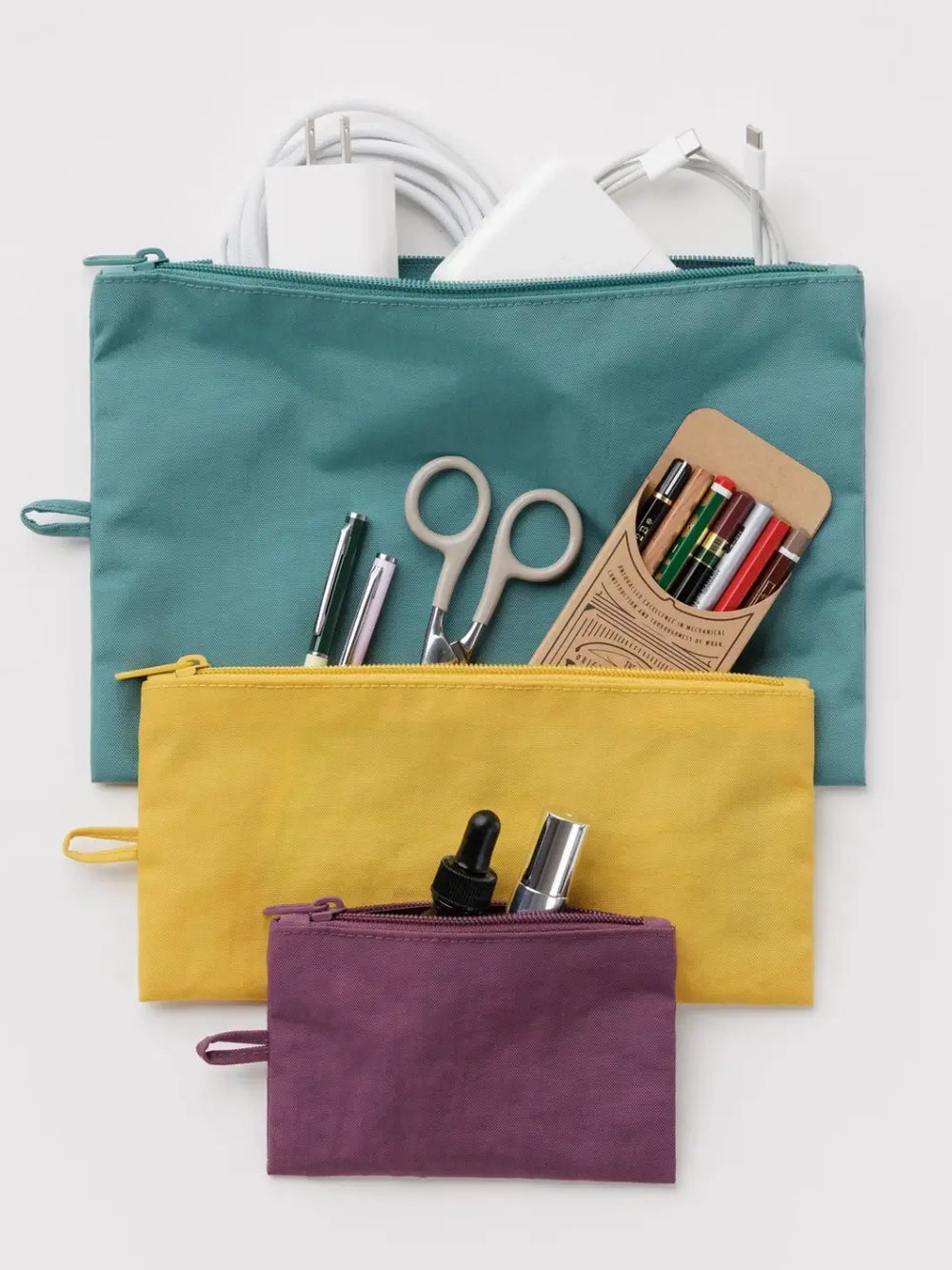 A stacked view of the BAGGU Flat Pouch Set in Jewel Mix filled with chargers, pens, scissors, and small cosmetics | Twentyseven
