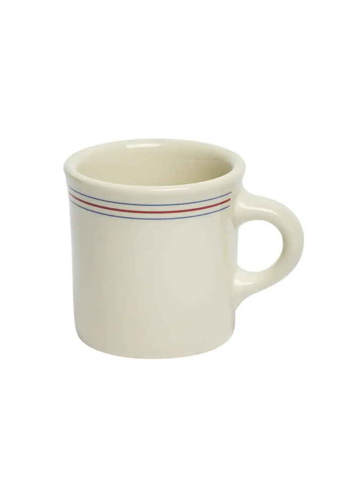An angled three-quarter view of an off-white HL Red/Blueband - Diner Mug (8.75oz) from Fishs Eddy, showing the inside of the rim, the side handle, and a red stripe between two blue stripes | Twentyseven Toronto