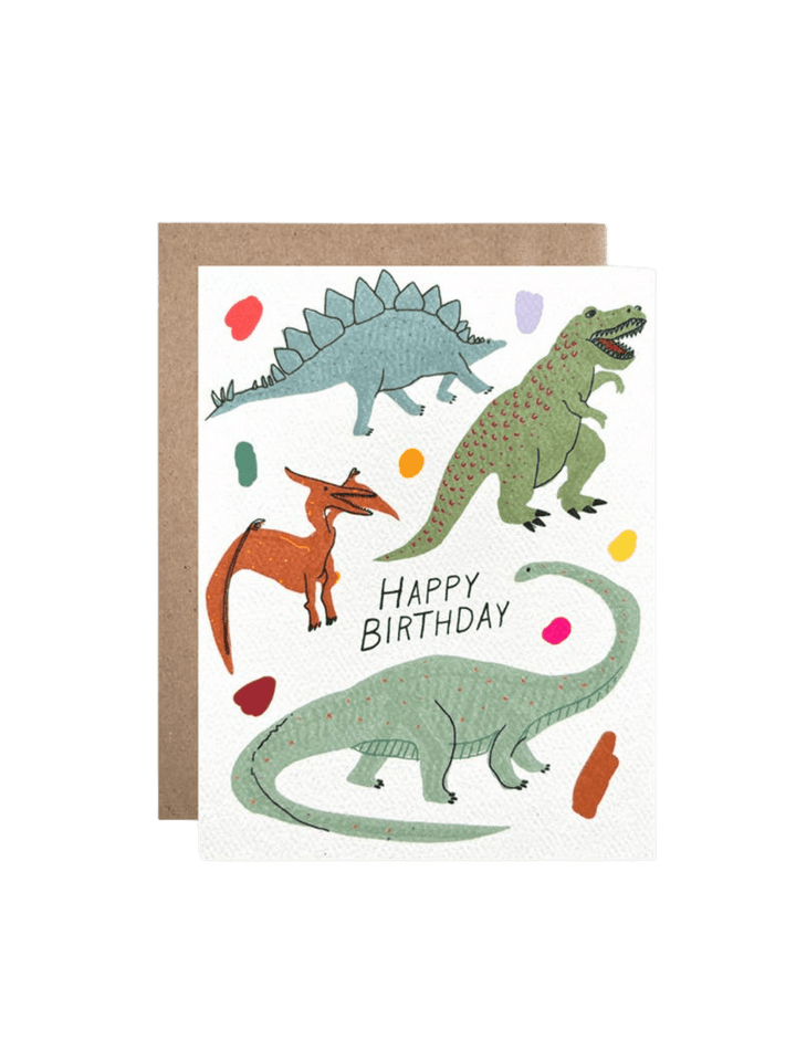A studio product shot of the Hartland Cards Happy Birthday Glow In The Dark Dinosaurs Card set against a brown kraft envelope | Twentyseven