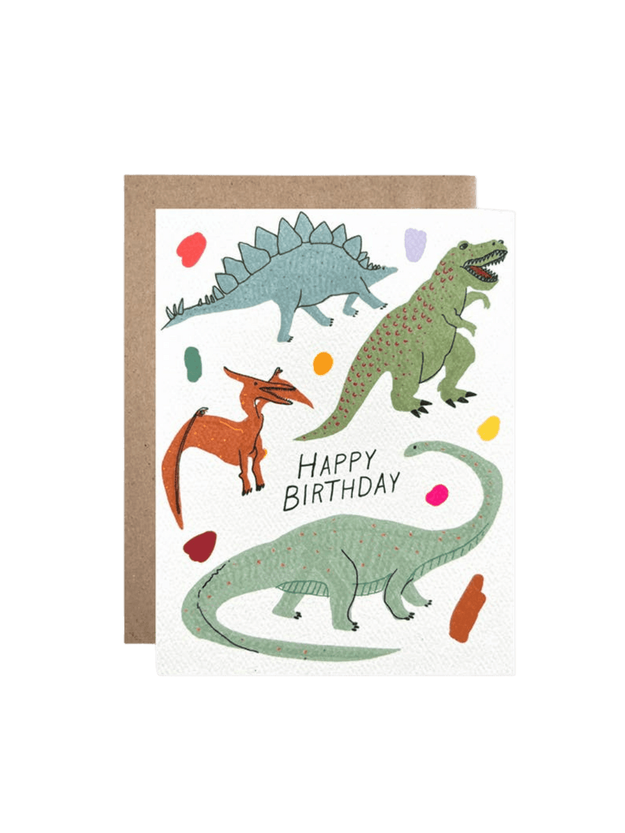 A studio product shot of the Hartland Cards Happy Birthday Glow In The Dark Dinosaurs Card set against a brown kraft envelope | Twentyseven