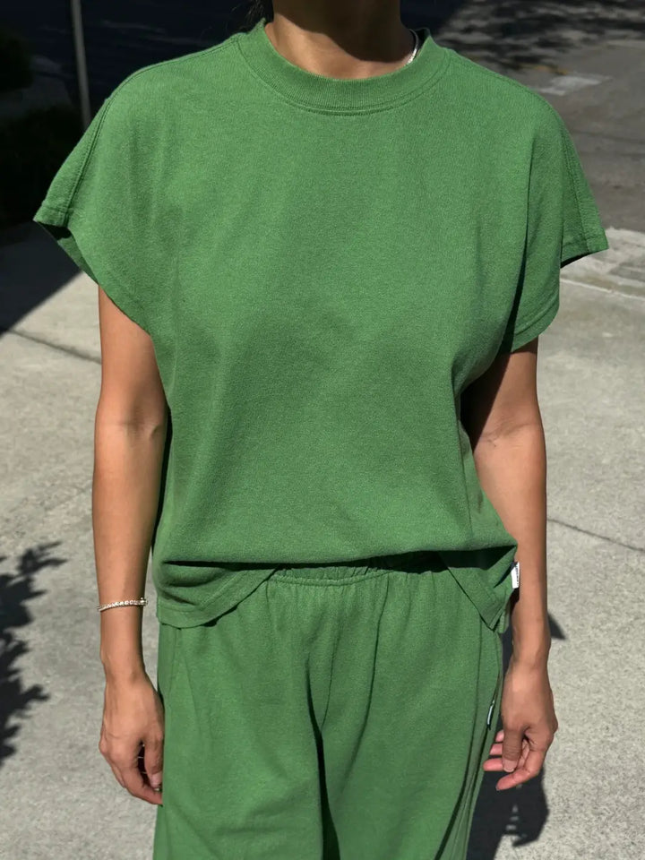 A front view shot of a model wearing the green short-sleeve Le Bon Shoppe Jeanne Tee in Asparagus paired with matching pants outdoors | Twentyseven