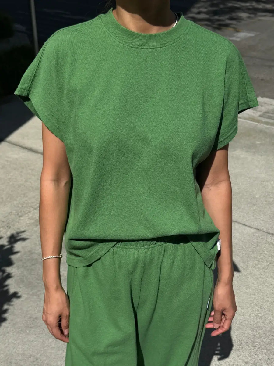 A front view shot of a model wearing the green short-sleeve Le Bon Shoppe Jeanne Tee in Asparagus paired with matching pants outdoors | Twentyseven
