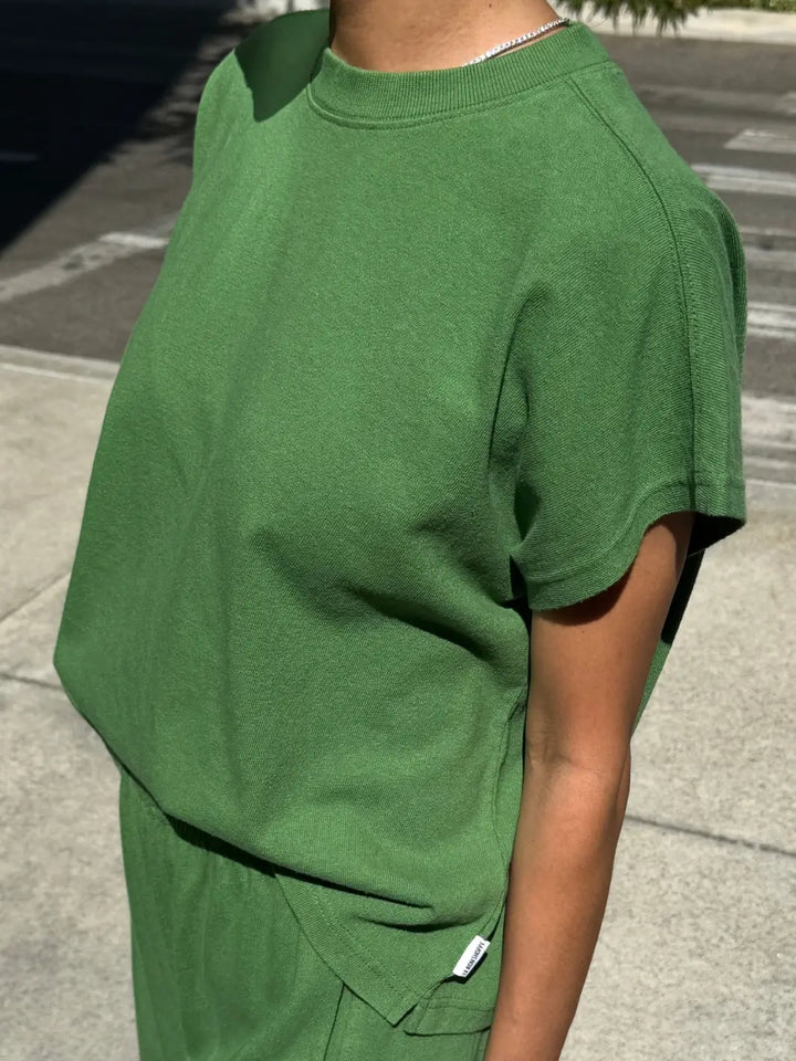 A side angle view of a model wearing the short-sleeve Le Bon Shoppe Jeanne Tee in Asparagus highlighting the cap sleeves and ribbed crew neckline | Twentyseven