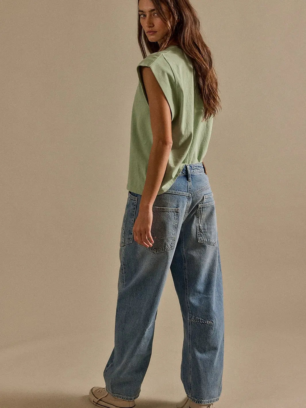 Rear three-quarter view of a model styled in a green tank top and the Free People We the Free Minimalist Moxie Barrel Jeans in County Fair | Twentyseven