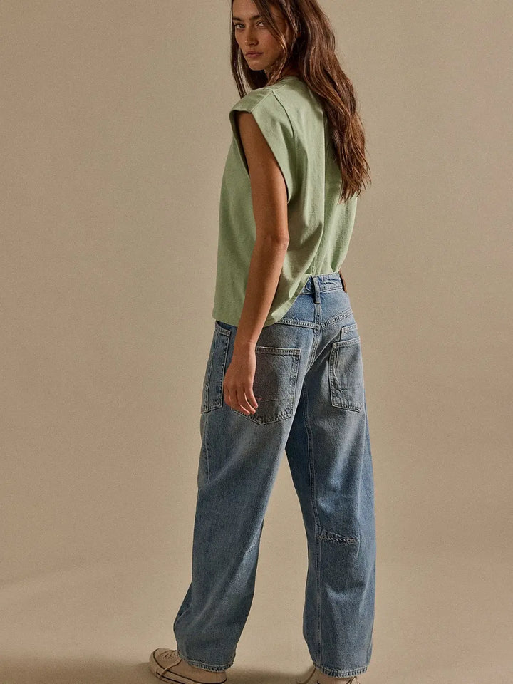 Rear three-quarter view of a model styled in a green tank top and the Free People We the Free Minimalist Moxie Barrel Jeans in County Fair | Twentyseven