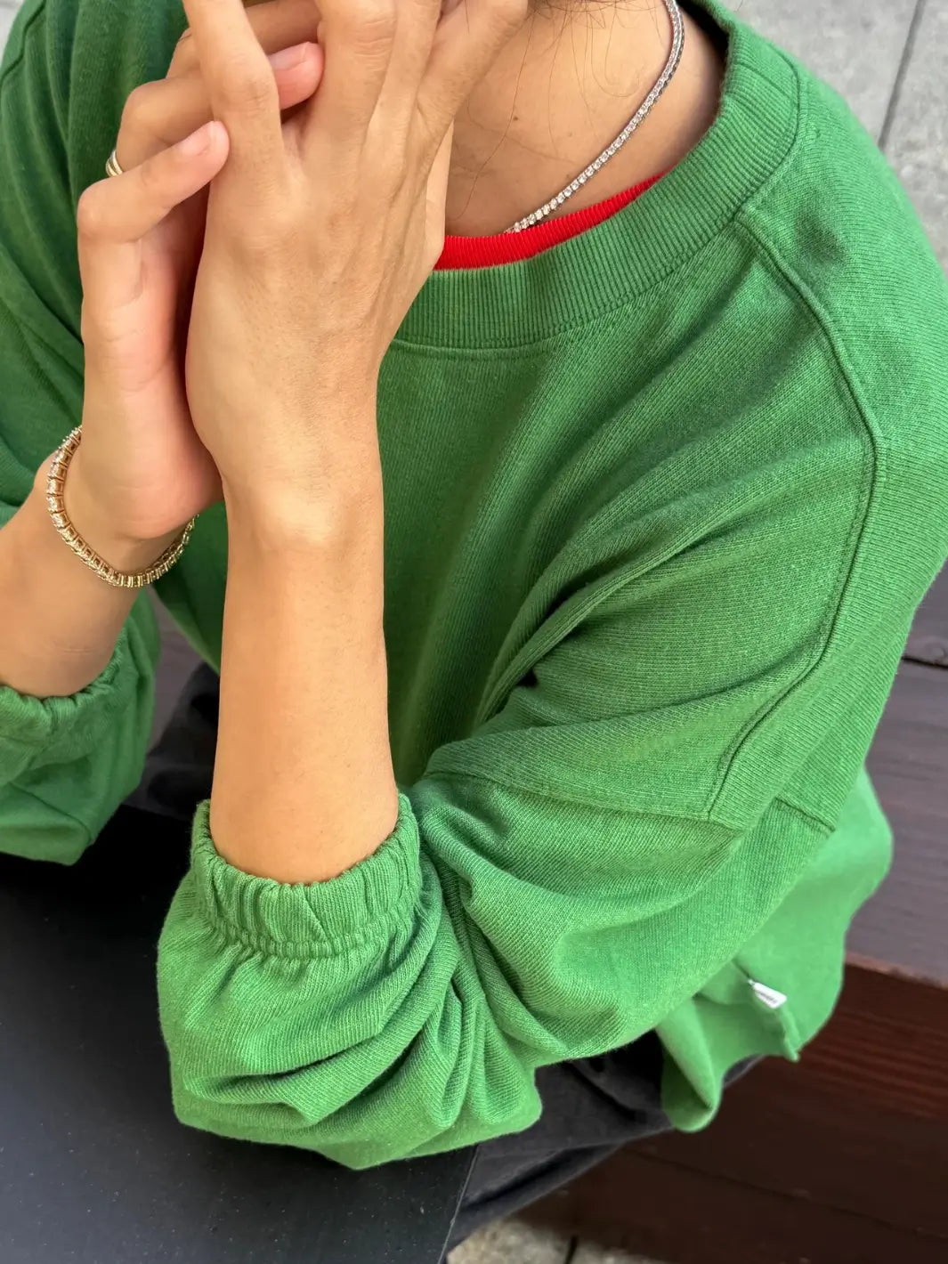 A close-up shot of a model resting their chin on their hands while wearing the Le Bon Shoppe Naturelle Tee in Asparagus highlighting the elastic cuffs | Twentyseven