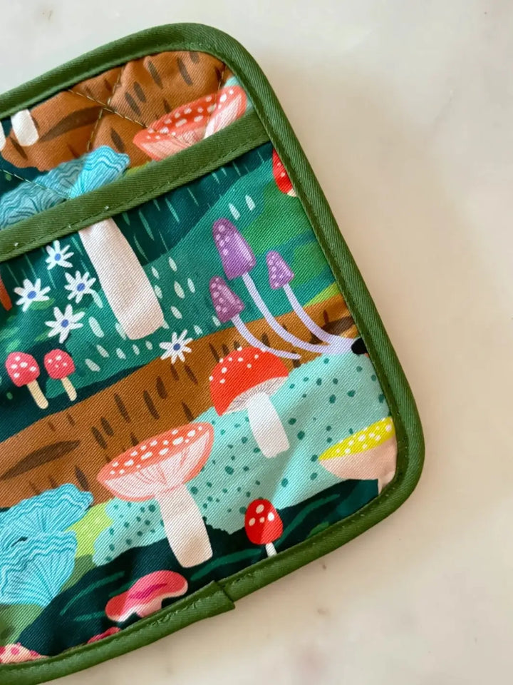 A close-up detail view of the quilted fabric on the Idlewild Co. Oven Mitt + Potholder Set - Mushroom Heaven showcasing vibrant red, yellow, and purple mushrooms set against a dark green trim | Twentyseven