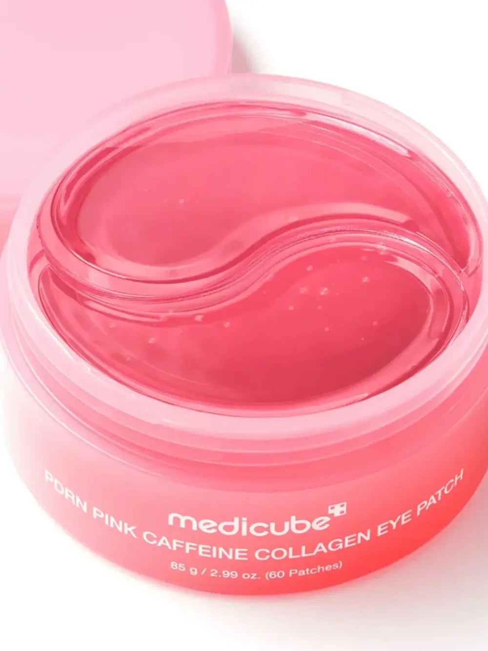 A close-up view looking down into an open jar of Medicube PDRN Caffeine Collagen Eye Patch showing the stacked, translucent pink hydrogel patches inside | Twentyseven