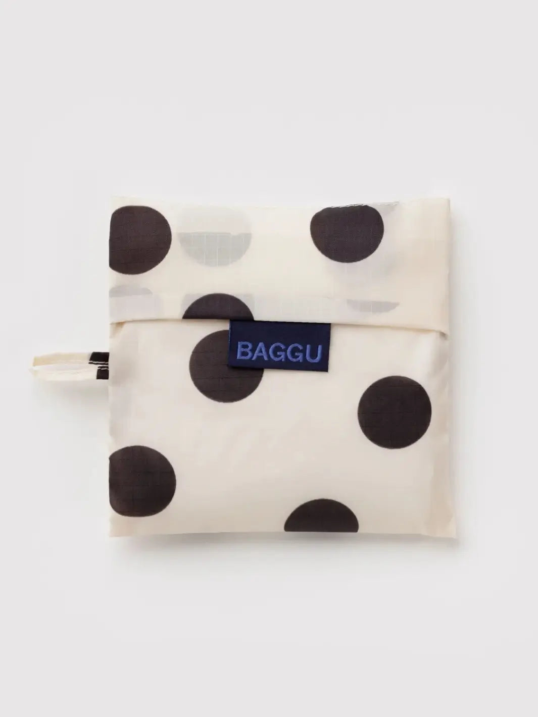 A top-down shot of the BAGGU Standard Baggu in Cream and Black Polka Dot folded into its matching square pouch | Twentyseven