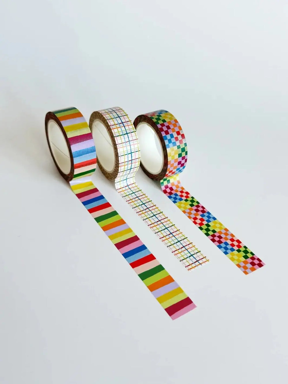 Three rolls of the Idlewild Co. Washi Tape, Set of 3 in Rainbow lined up vertically and unrolled to display their colourful striped, fine plaid, and checkered designs against a white background | Twentyseven