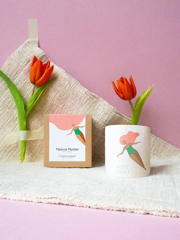 Maison Matine A Contre Courant Scented Candle with a design of a woman in a green swimsuit, accompanied by tulips on a pink background 160g | Twentyseven Toronto