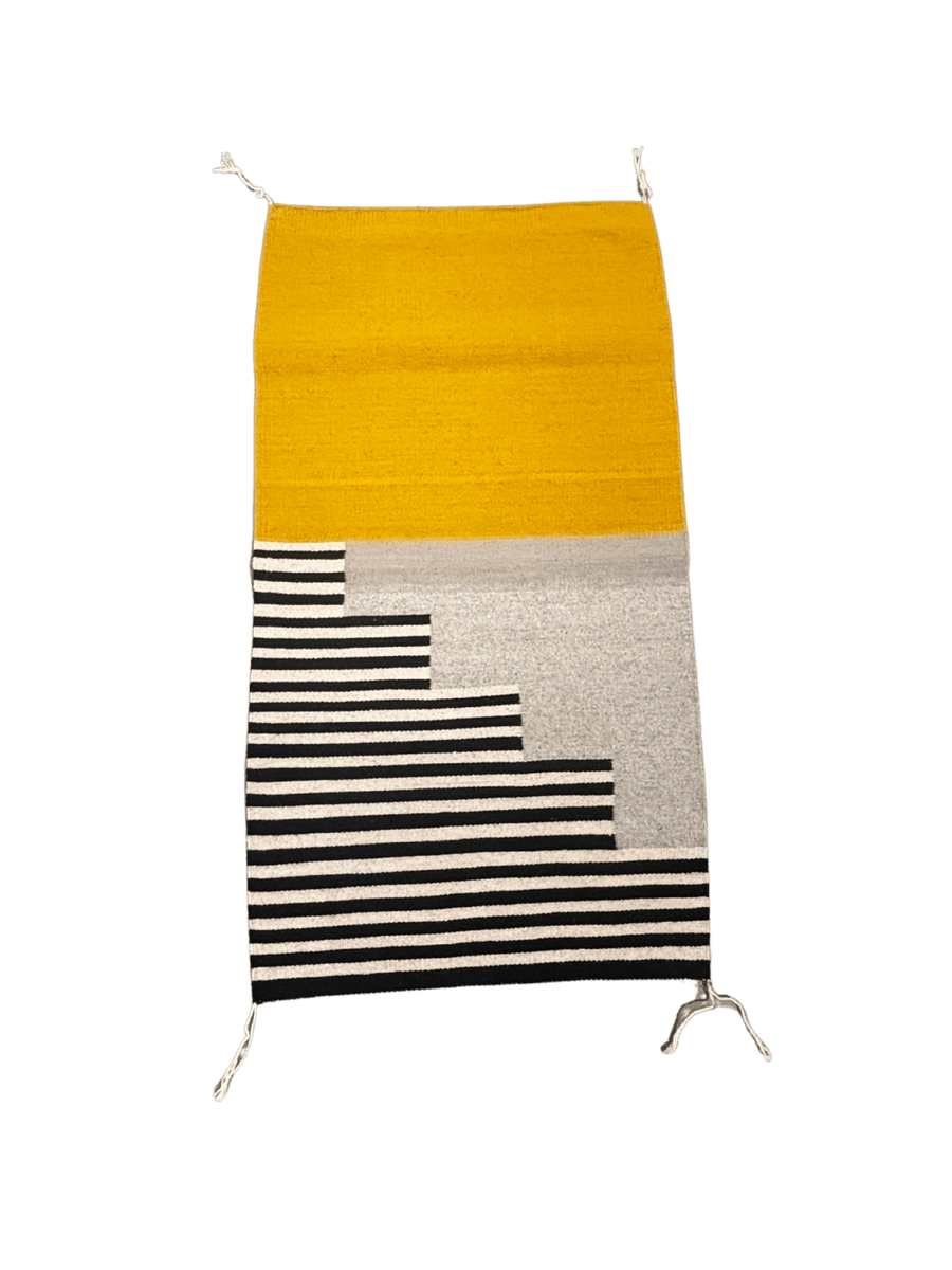 Handwoven modern rug with a mustard yellow upper half and stepped black-and-cream striped pattern along the bottom on a soft grey background | Twentyseven Toronto