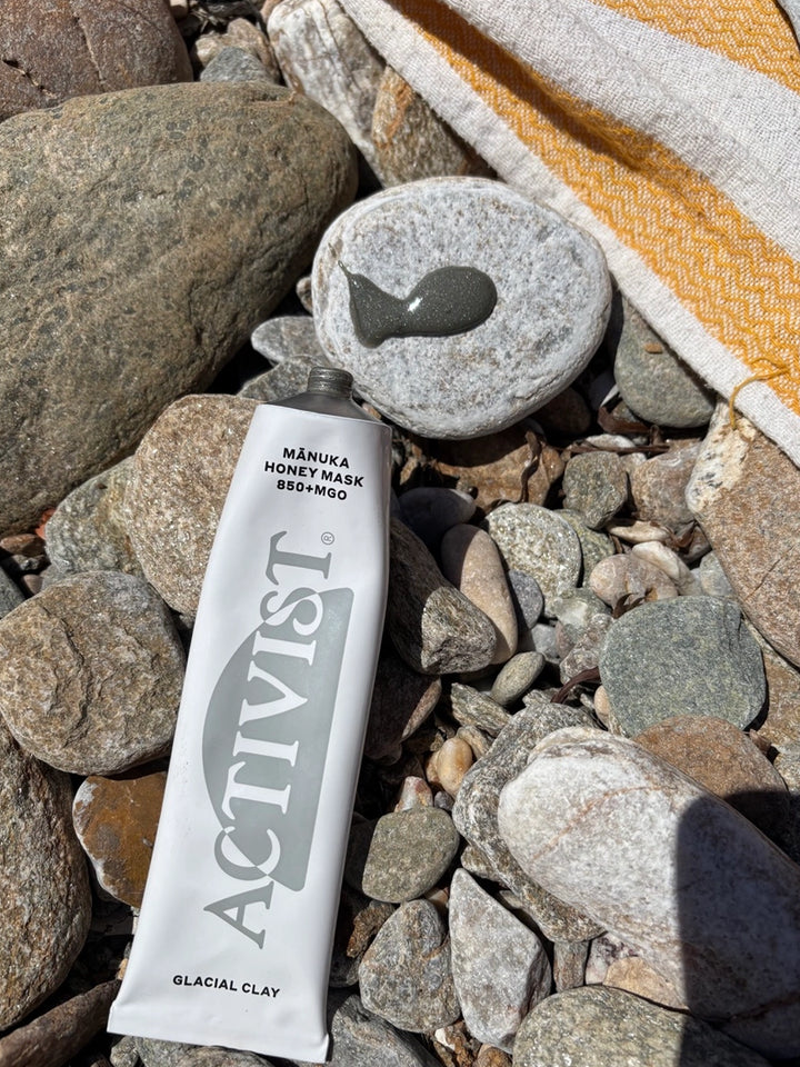 ACTIVIST Mānuka Honey Glacial Clay Mask tube and clay mask texture styled on rocks by the water | Twentyseven Toronto