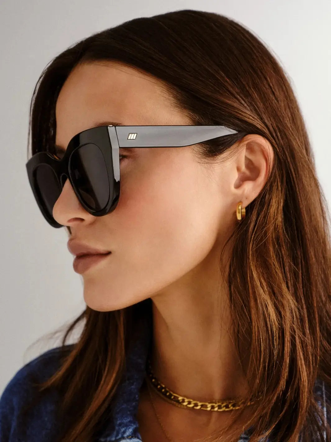 A side-profile view of a woman wearing the Le Specs Air Heart - Black sunglasses | Twentyseven Toronto