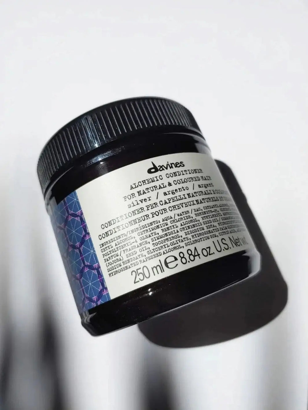 A dark jar of Davines ALCHEMIC Silver Conditioner at an angle on a white surface  | Twentyseven Toronto