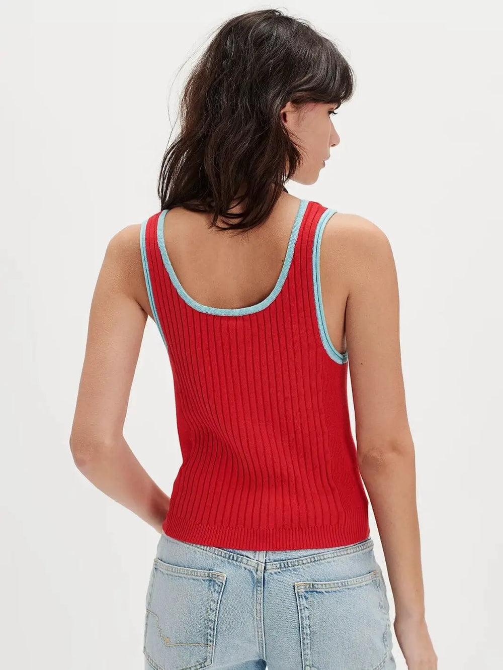 A view from behind highlights the scoop neckline and light blue trim details of the vibrant Free People All Star Sweater Tank - Atlas Red Combo styled with light-wash denim | Twentyseven Toronto