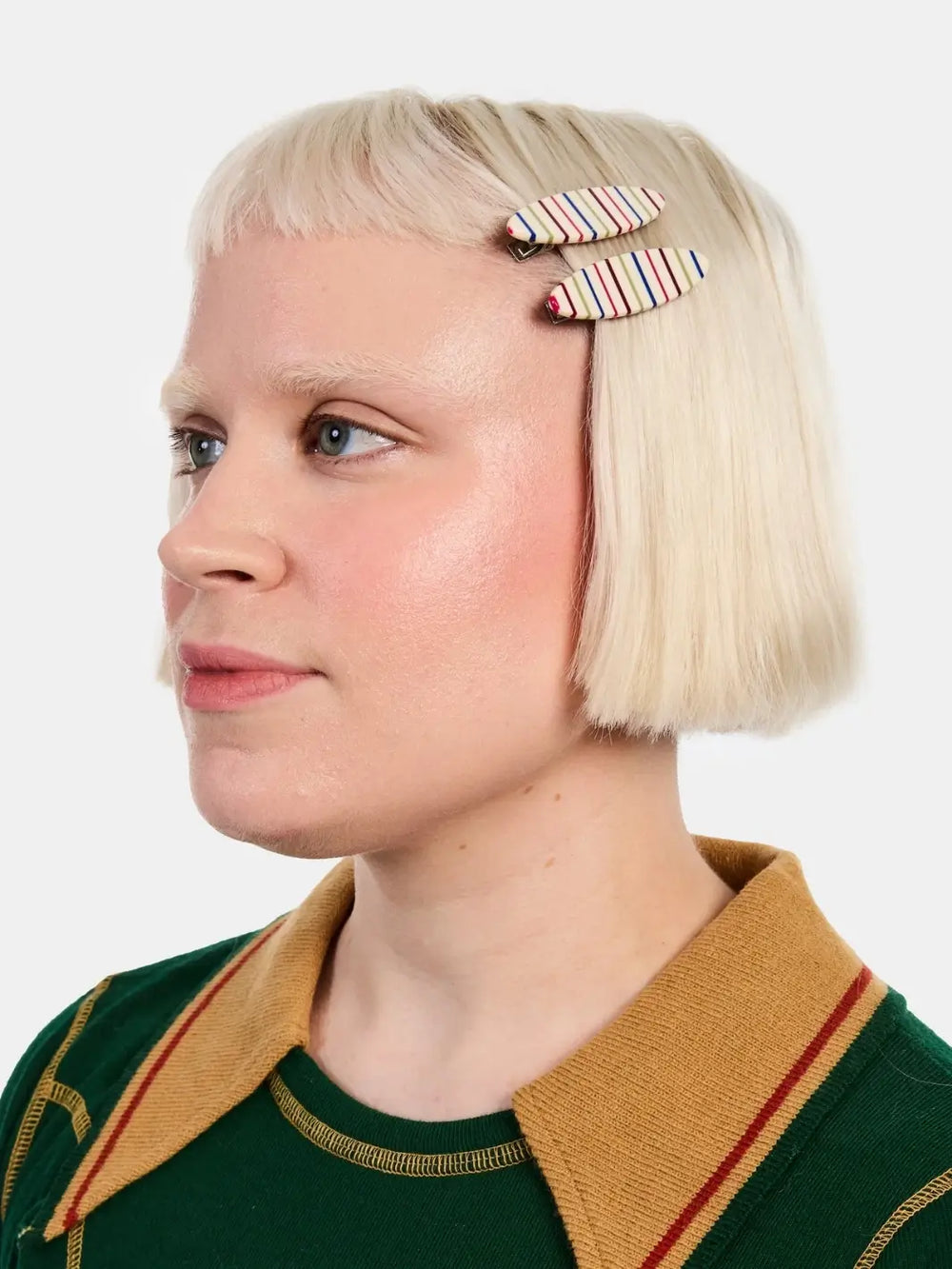 A person with short blonde hair wears two colorful, striped Chunks Hairclips Allie Clips in Oval Vanilla Stripe pinned back on the side of their head | Twentyseven Toronto