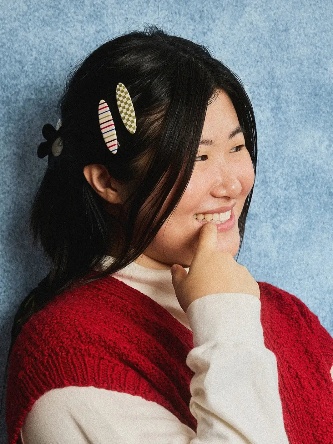 A person with dark hair wears two oval hair accessories, including one Chunks Hairclips Allie Clips in Oval Vanilla Stripe alongside a green checkered hairclip | Twentyseven Toronto