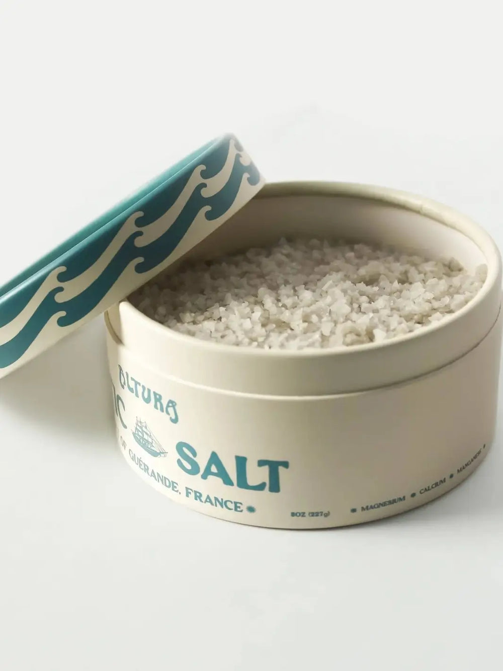 A round container of Altura Celtic Sea Salt is shown with its lid partially removed, revealing the coarse, mineral-rich grey salt crystals inside | Twentyseven Toronto