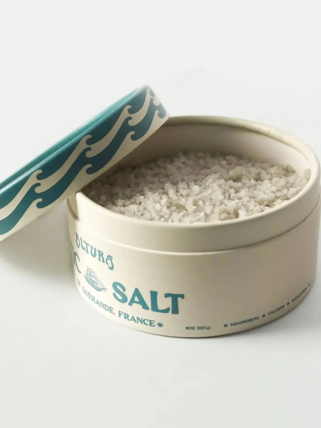A round container of Altura Celtic Sea Salt is shown with its lid partially removed, revealing the coarse, mineral-rich grey salt crystals inside | Twentyseven Toronto