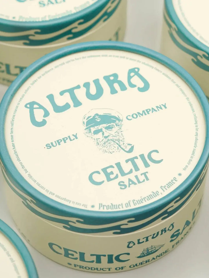 A close-up shot focuses on the lid of a round paper tube of Altura Celtic Sea Salt, featuring a nautical logo of a bearded sailor with a pipe | Twentyseven Toronto