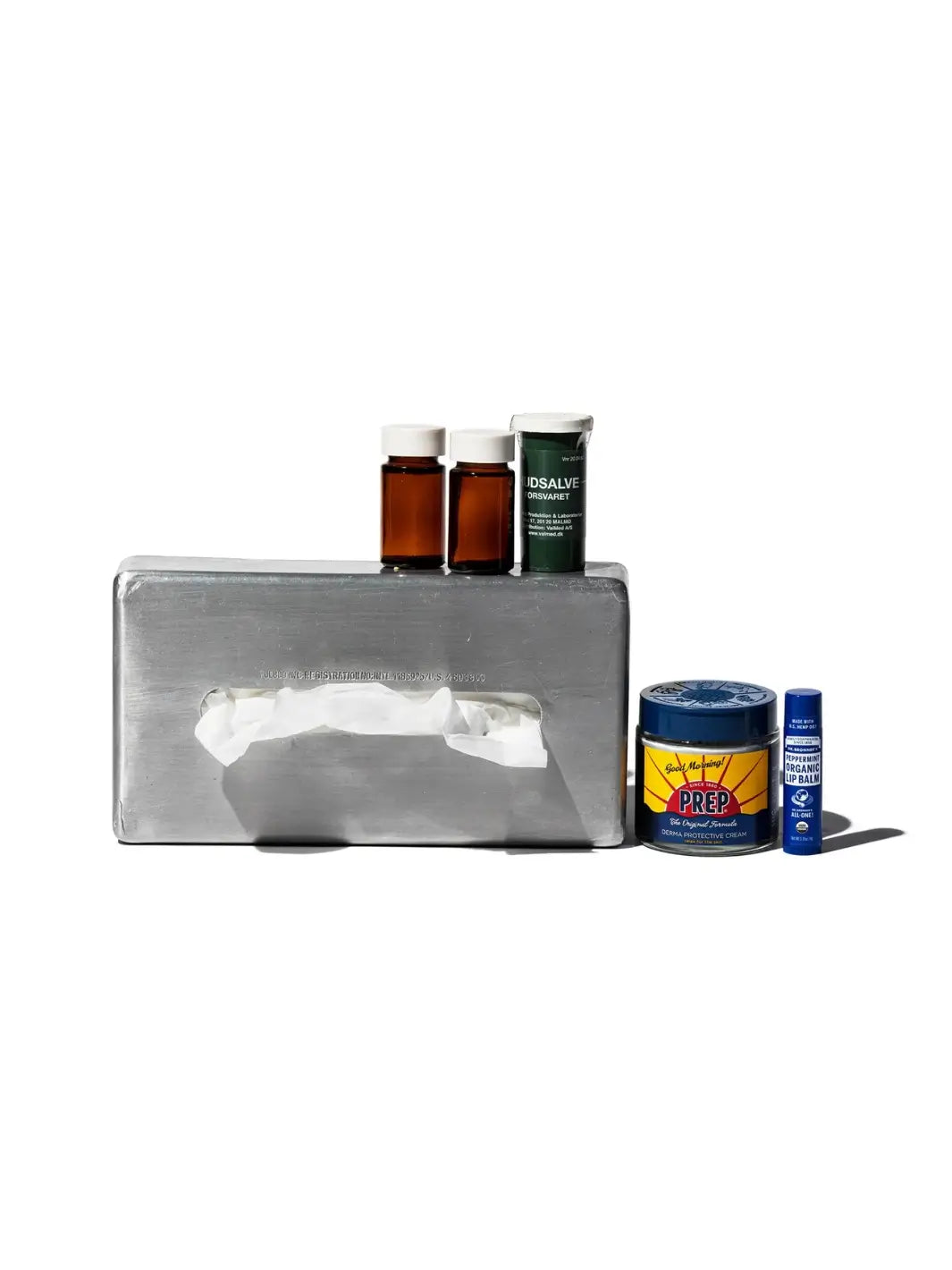 Small amber and green medicine bottles rest on top of the Aluminum Tissue Case from Puebco | Twentyseven Toronto