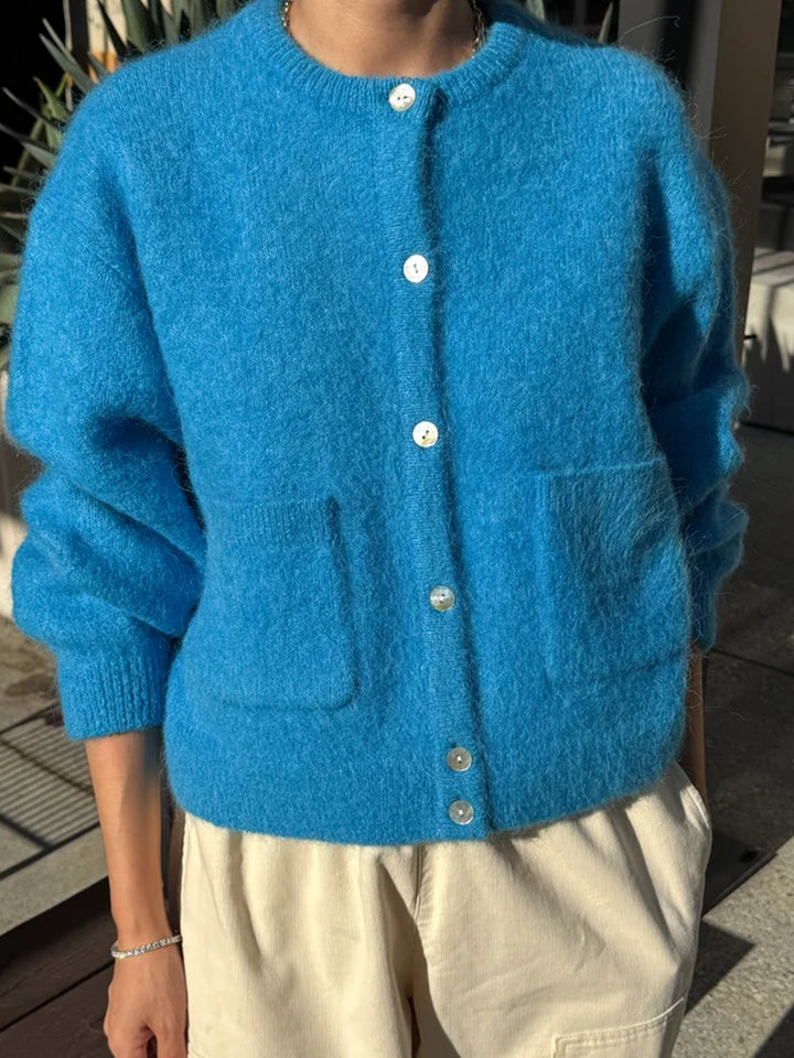Model wearing the Le Bon Shoppe Amelie Cardigan in turquoise blue with cream trousers, showing its relaxed fit, soft fuzzy knit and front patch pockets | Twentyseven Toronto