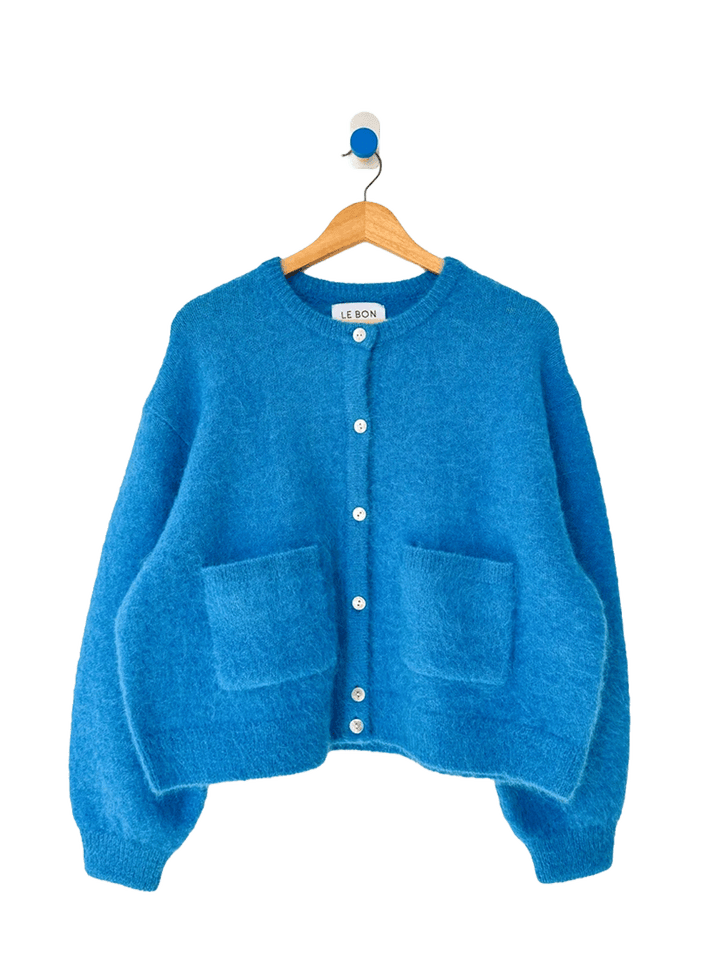 Turquoise blue Le Bon Shoppe Amelie Cardigan on a wooden hanger, featuring a fuzzy knit texture, button front, crew neckline and two patch pockets | Twentyseven Toronto