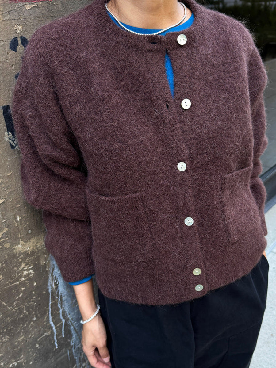 Amélie Alpaca Cardigan in Chocolate styled with a blue top and black trousers, featuring shell buttons and front patch pockets | Twentyseven Toronto