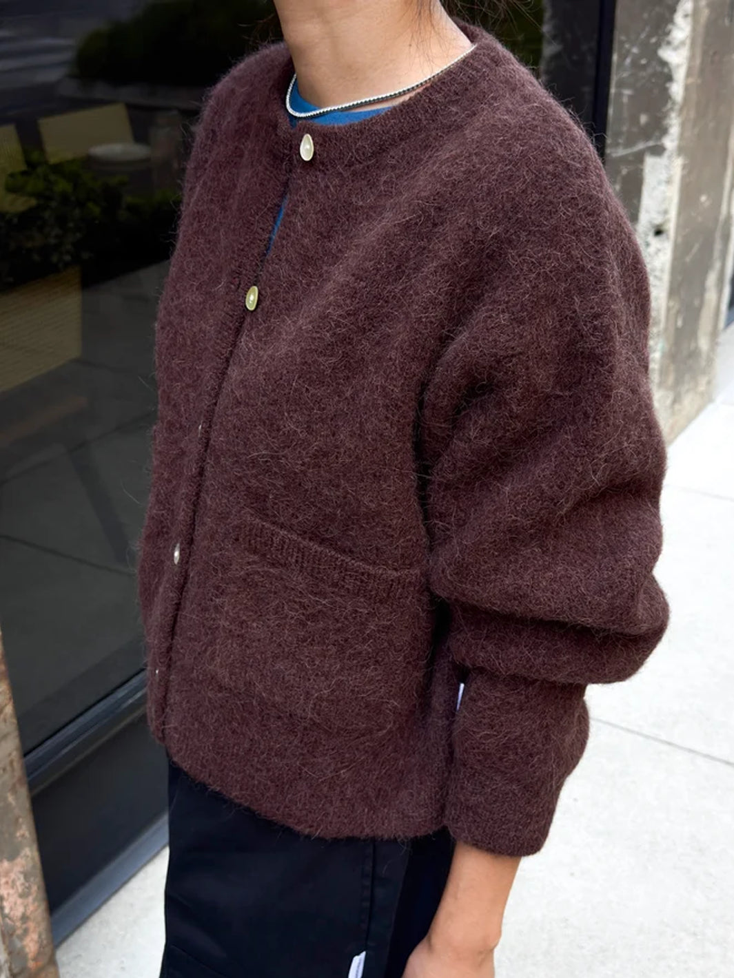 Amélie Alpaca Cardigan in Chocolate worn over a blue top, showing its soft textured knit, relaxed fit and balloon sleeves | Twentyseven Toronto