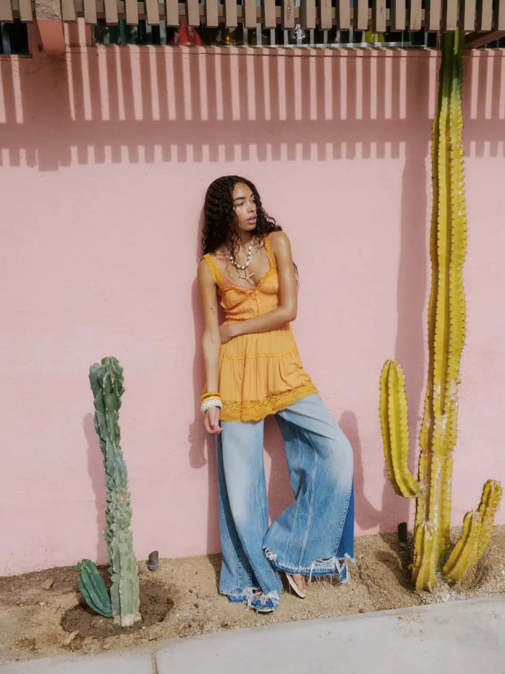 A model leans against a pink wall next to cacti, highlighting the flowy structure and panel accents of the Free People Apollo Wide Leg in Streamline | Twentyseven Toronto