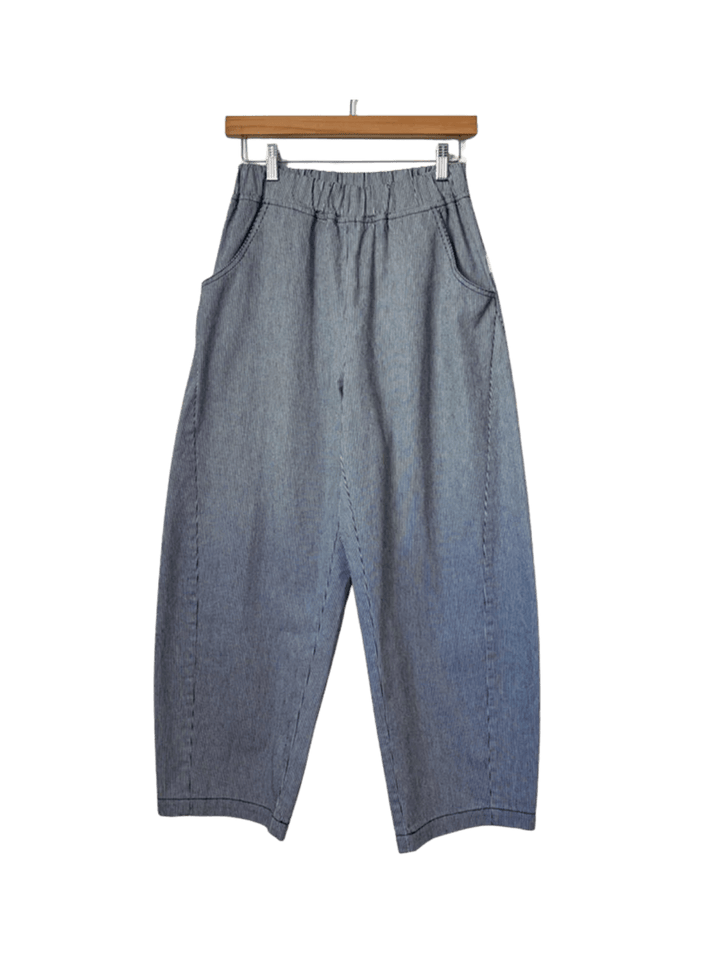 Grey and blue striped Le Bon Shoppe Arc Pants - Blue Stripe are shown straight-on, hanging from a wooden pants hanger with metal clips | Twentyseven Toronto