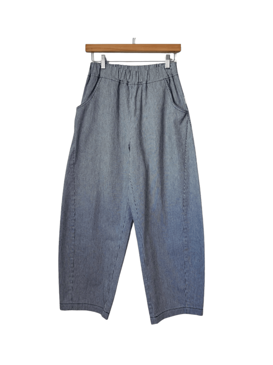 Grey and blue striped Le Bon Shoppe Arc Pants - Blue Stripe are shown straight-on, hanging from a wooden pants hanger with metal clips | Twentyseven Toronto